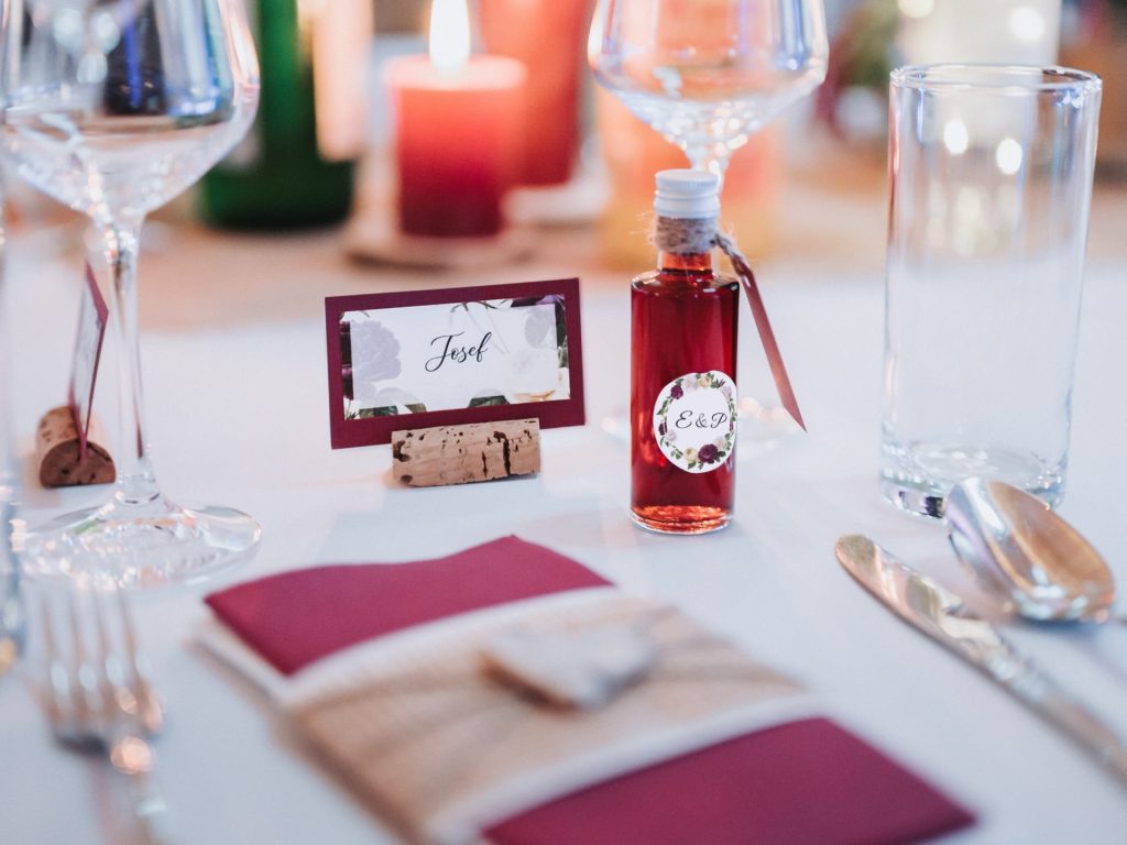 Tischkärtchen und Schnaps-Flaschenetikett mit floralem Hintergrund und geschwungener Schrift